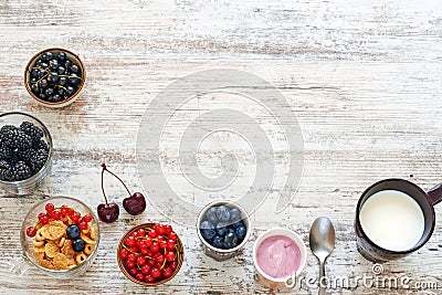 Yogurt, fresh berries, cornflakes and cup of milk on a wooden table. Stock Photo