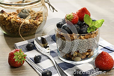 Yogurt with granola, fresh blueberries, chia seeds and oats in a glass over wood background. close up Stock Photo