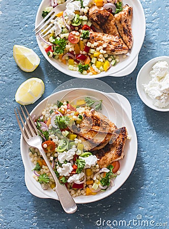 Yogurt marinated grilled chicken breast and israeli couscous and vegetables tabouli salad on a blue background Stock Photo