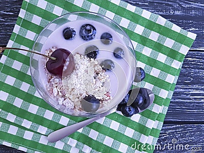 Yogurt oatmeal jar cherry, dessert homemade blueberry glass on a black wooden background Stock Photo