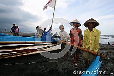 The fishermen are working together to lift and push the boats to shore Editorial Stock Photo