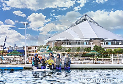 Young people interacting with a Beluga whale at Hakkeijima Sea Paradise. Editorial Stock Photo