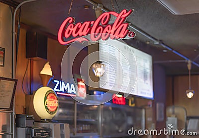 Neon logos of famous soda brands lighting up the interior of an American fast food. Editorial Stock Photo