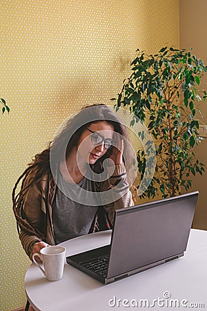 Woman wearing glasses and casual clothes touch her head while working on computer at home, stress and fatigue concept Stock Photo