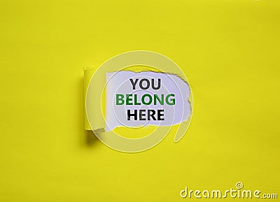 You belong here symbol. Concept words `You belong here` appearing behind torn yellow paper. Beautiful yellow background. Busines Stock Photo
