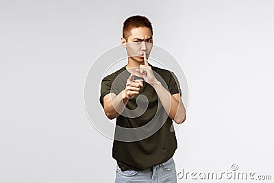 You better keep mouth shut. Portrait of angry serious-looking asian man pointing at camera and shushing scolding you for Stock Photo