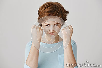 You better not mess with me, boy. Emotive cute redhead european woman looking from under the brows holding fists near Stock Photo