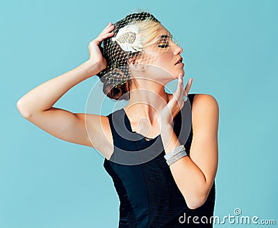 You can never be overdressed. Studio shot of an elegantly dressed young woman posing against a blue background. Stock Photo