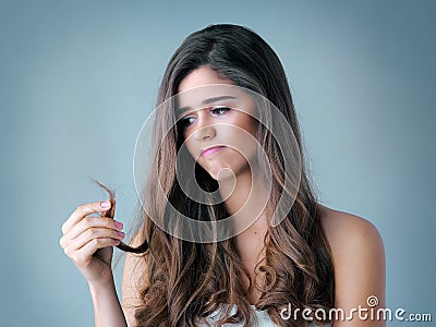 Are you doing more bad than good to it. Studio shot of a beautiful young woman looking at her split ends. Stock Photo