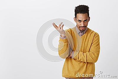 Are you dumb. Portrait of annoyed good-looking male with afro haircut in yellow clothes, gesturing, expressing confusion Stock Photo