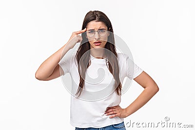 Are you dumb. Portrait of skeptical and bothered, annoyed young woman roll finger over temple and staring with disdain Stock Photo