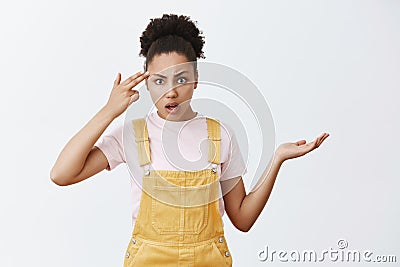 Are you insane or dumb. Portrait of displeased and annoyed questioned female with dark skin, shrugging with Stock Photo