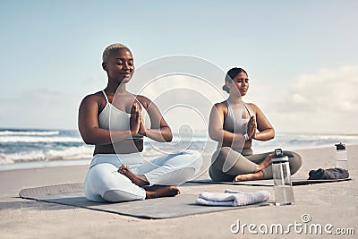 You inspired me to tap into my inner yogi. two young women meditating during their yoga routine on the beach. Stock Photo