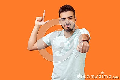 You are loser! Portrait of bossy angry brunette man showing loser gesture and pointing at camera. isolated on orange background Stock Photo