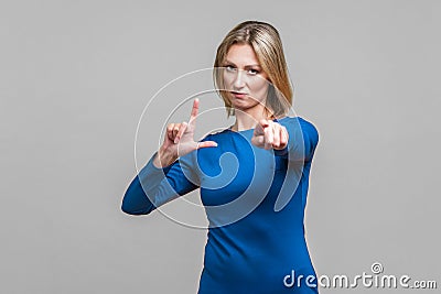 You are loser! Portrait of bossy serious businesswoman showing loser gesture and pointing at camera. isolated on gray background Stock Photo
