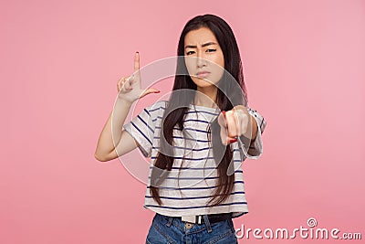 You lost! Portrait of dissatisfied girl with brunette hair in striped t-shirt showing loser or lame gesture Stock Photo