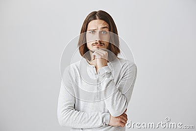 You made me interested and curious, tell details. Portrait of handsome young male with beard and long hair holding hand Stock Photo