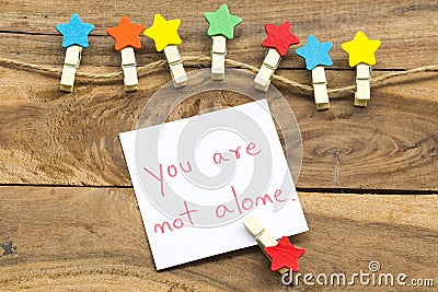 You are not alone message card handwriting with colorful wooden star clips arrangement flat lay postcard style Stock Photo