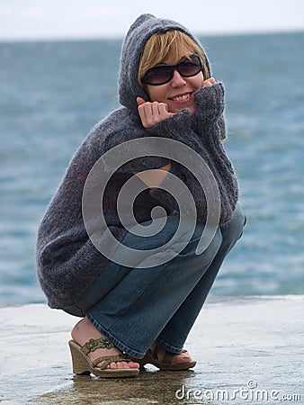 Youn Lady in Hood Sitting near Sea Stock Photo