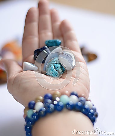 Yound woman is holding a collection of blue raw mineral gemstones in her palm Stock Photo