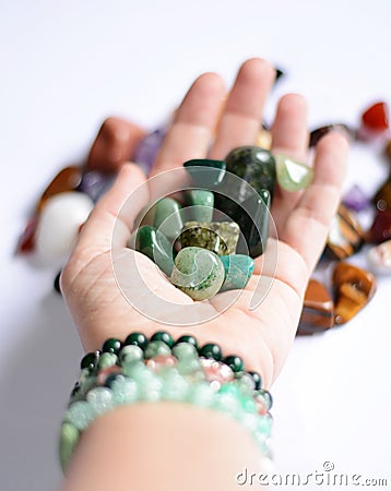 Yound woman is holding a collection of green raw mineral gemstones in her palm Stock Photo