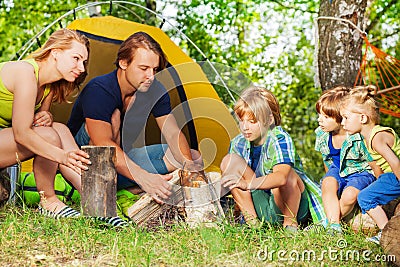 Young active family making camp fire in the woods Stock Photo