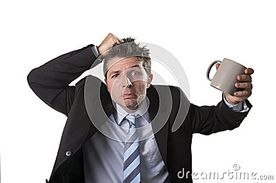 Young addict business man in suit and tie holding empty cup of coffee anxious Stock Photo