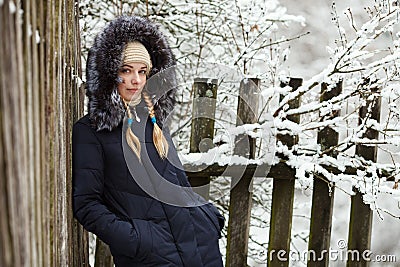 Young adorable woman wearing blue hooded coat enjoying strolling in winter forest outdoors. Nature cold season freshness concept. Stock Photo