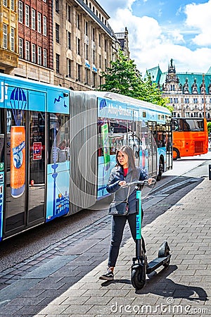 Young adult Asian female on electric scooter in front of The Town Hall in Hamburg, Germany Editorial Stock Photo