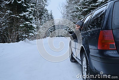 Young adult attractive Caucasian man sits at the wheel of his car snowy winter day. Wintertime road trip. Happy smiling Stock Photo