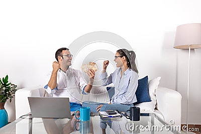 Young adult couple very happy earning money online on the couch, in the living room at home Stock Photo