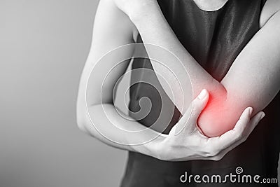 Young adult female with her muscle pain on gray background. Woman having elbow ache due to lateral epicondylitis or tennis elbow. Stock Photo