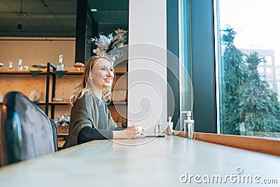 Young adult forty years blonde woman in casual clothes drinking coffee using mobile at cafe Stock Photo