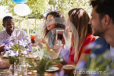 Young adult friends socialising at a table in a garden Stock Photo