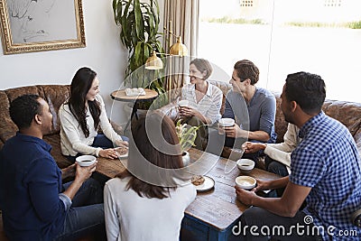 Young adult friends talking around a table at a coffee shop Stock Photo