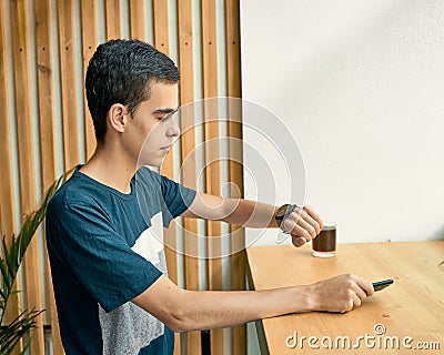 Young adult looks at the clock, waiting for a meeting with friends. A man is waiting for a woman in a cafe on a date, looking at Stock Photo