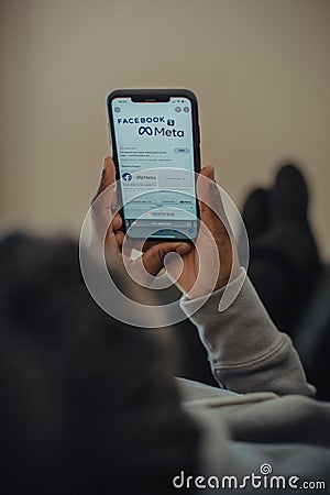 Young adult male holding an iPhone in hand while looking attentively at the screen Editorial Stock Photo