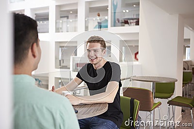 Young adult male students talking in modern university cafe Stock Photo