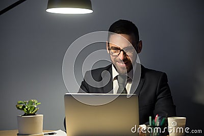 Young adult man working on laptop computer late at night. Stock Photo