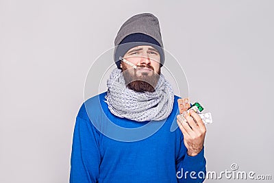 Young adult sick man have temperature, holding many pills. Stock Photo