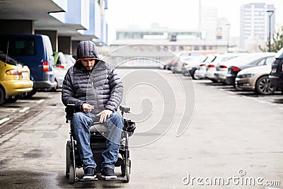 Young, adult wheelchair user on a parking lot with copy space Stock Photo