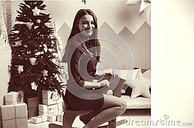 Young adult woman have fun with white toy horse on new years eve. happy new year holiday. girl sit against green christmas tree. g Stock Photo