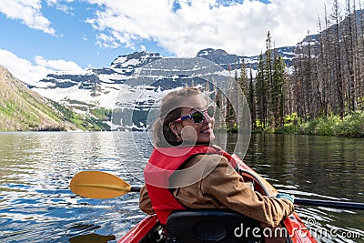 Young adult woman kayaks on Cameron Lake in Waterton National Park, enjoying the glacier scenery Stock Photo
