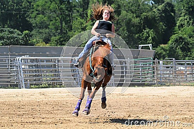 Young adult woman riding a bucking horse Stock Photo