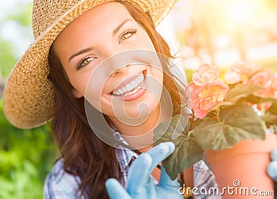 Young Adult Woman Wearing Hat and Gloves Gardening Outdoors Stock Photo