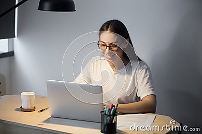 Young adult woman working on laptop computer late at night. Stock Photo