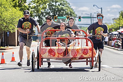 Young adults push bed down city street in fundraising event Editorial Stock Photo