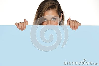 A young advertizing smiling woman peeks behind a empty board Stock Photo