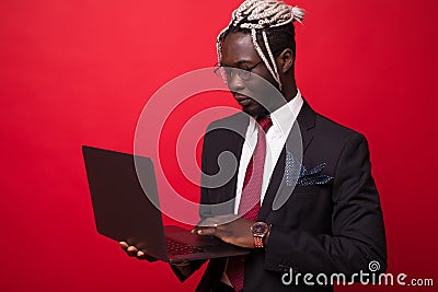 Young african american businessman using computer laptop with a happy face standing with a confident smile isolated on red Stock Photo