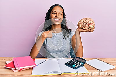 Young african american girl holding brain studying for school pointing finger to one self smiling happy and proud Stock Photo